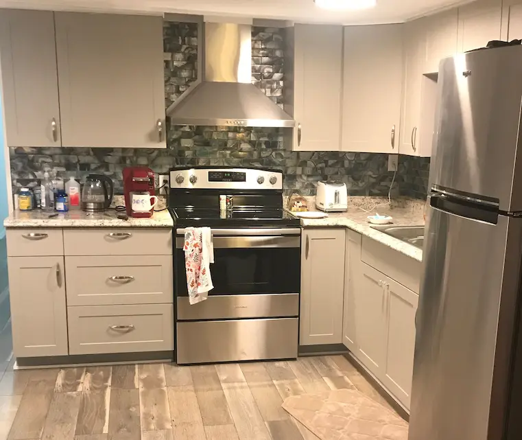 Photo of the trailer interior showcasing new appliances, new flooring, and admired backsplash.